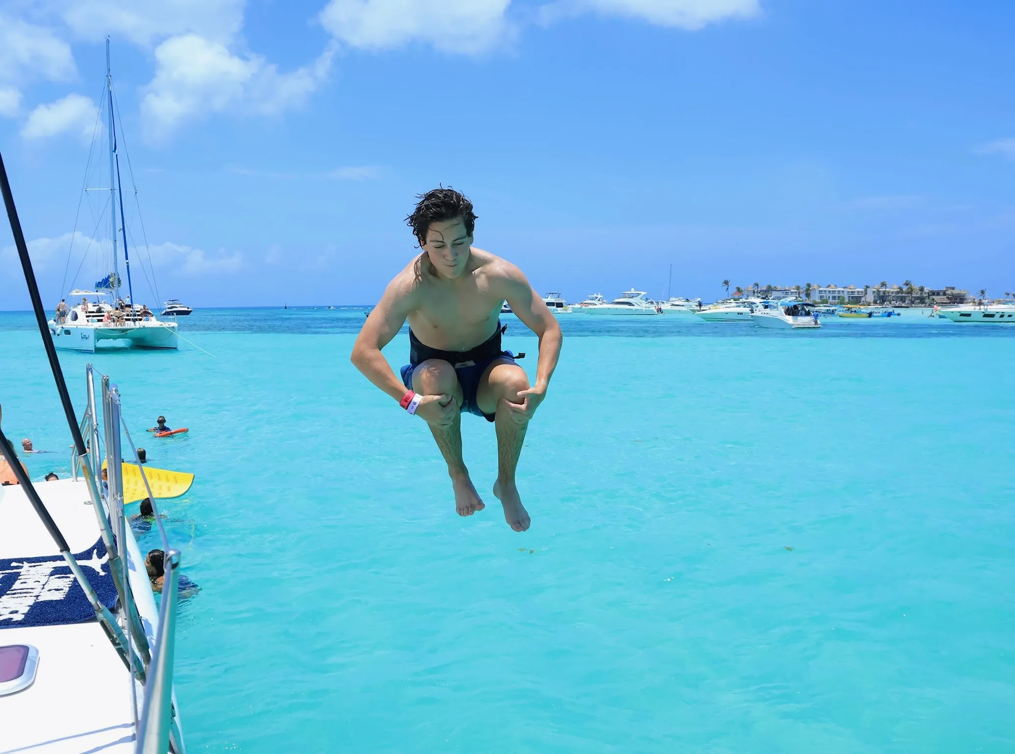 Jumping off the catamaran into turquoise water, boats anchored in the distance