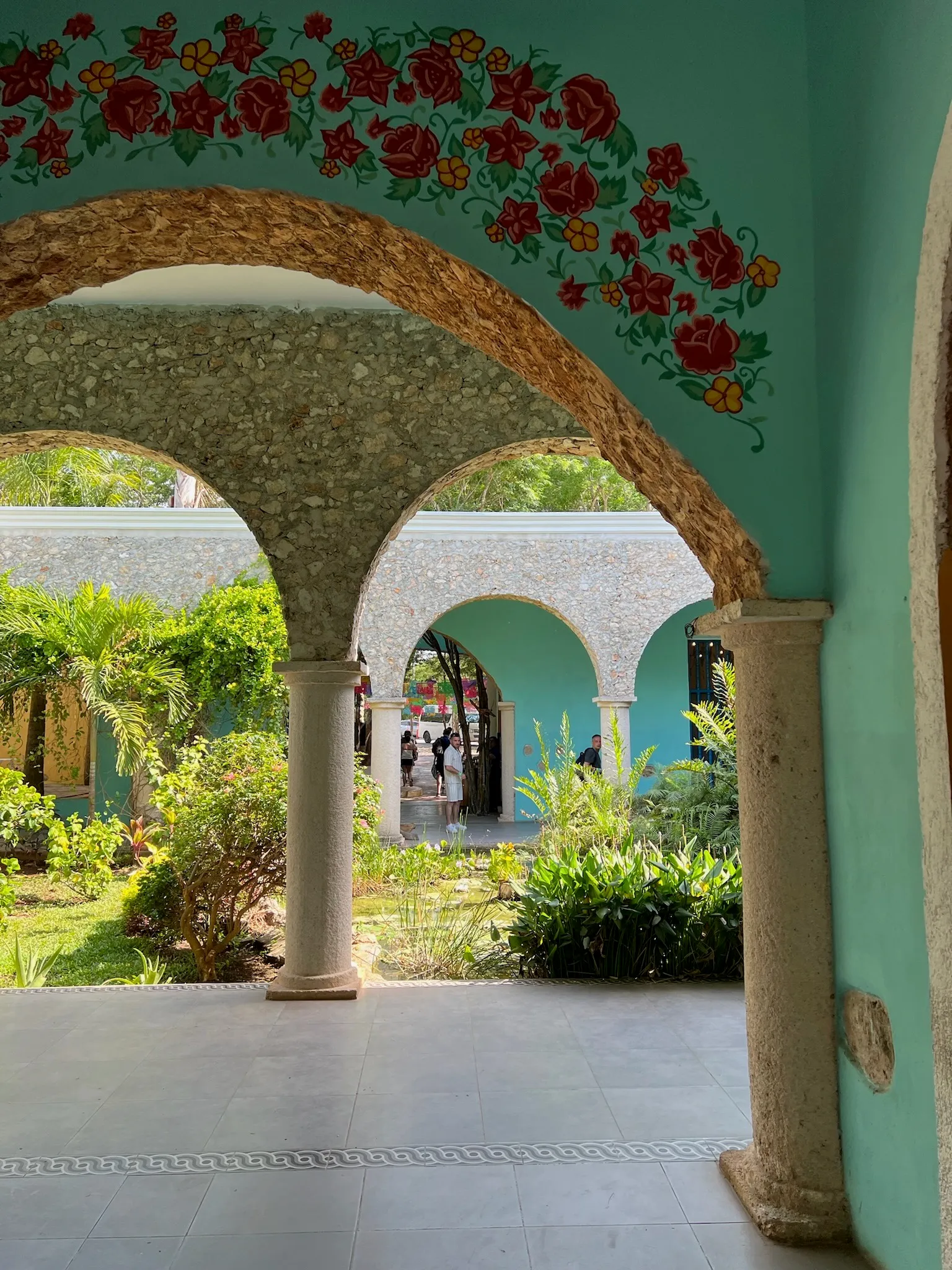 A hand-painted flower mural over a stone archway, more arches receding into the courtyard